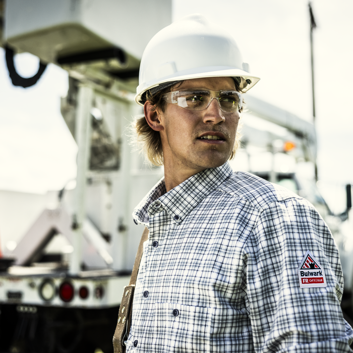 Person wearing a hard hat and safety glasses with a truck in the background